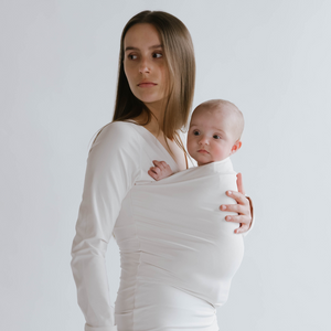 Side view of a female wearing a newborn in a Natural long sleeve Soothe Shirt.