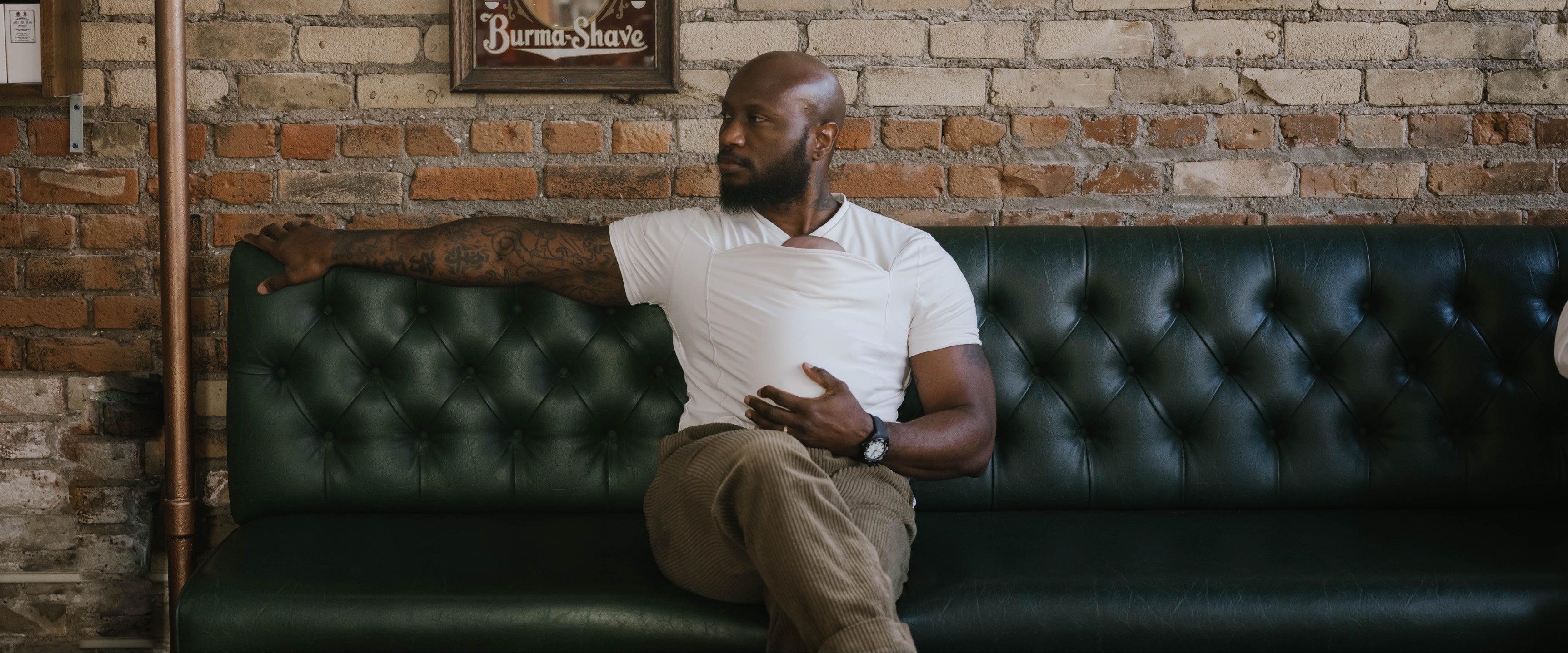 Dad wearing his newborn in a Natural Dad Shirt while sitting on a couch.