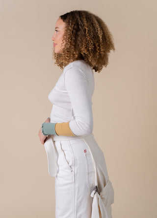 woman dressed in all white looking to the left with the simple wrap around her waist. 