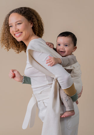 woman dressed in all white with a baby on her back in a cream simple wrap