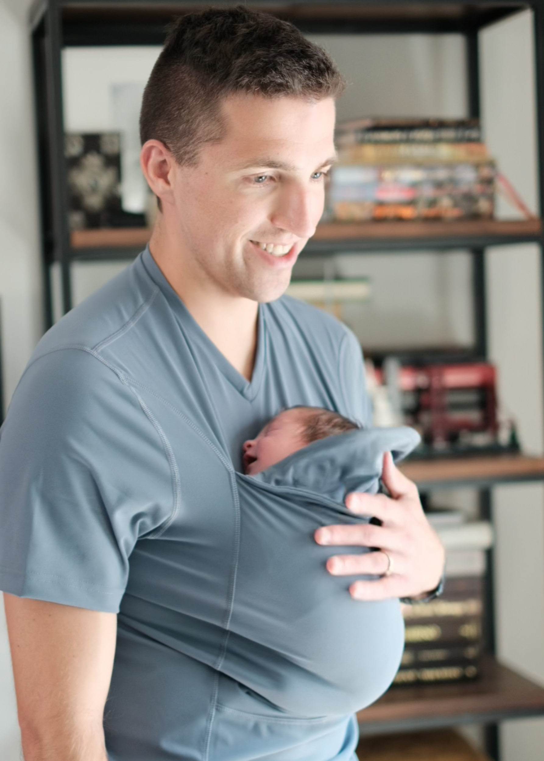 Angled view of dad snuggling the newborn in the pouch of his Brook Dad Shirt.