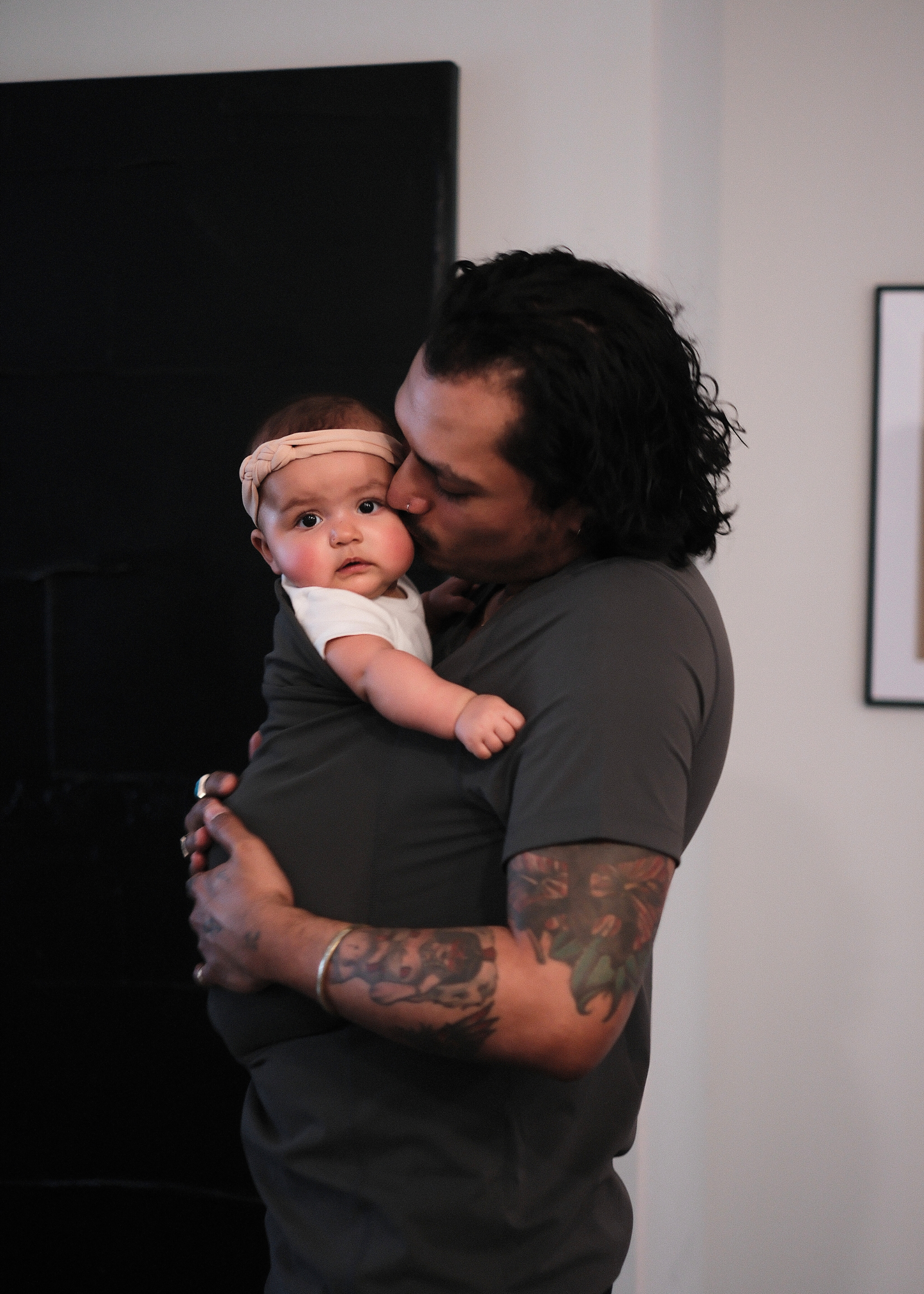 Dad kissing the baby in the pouch of his Gray Dad Shirt.
