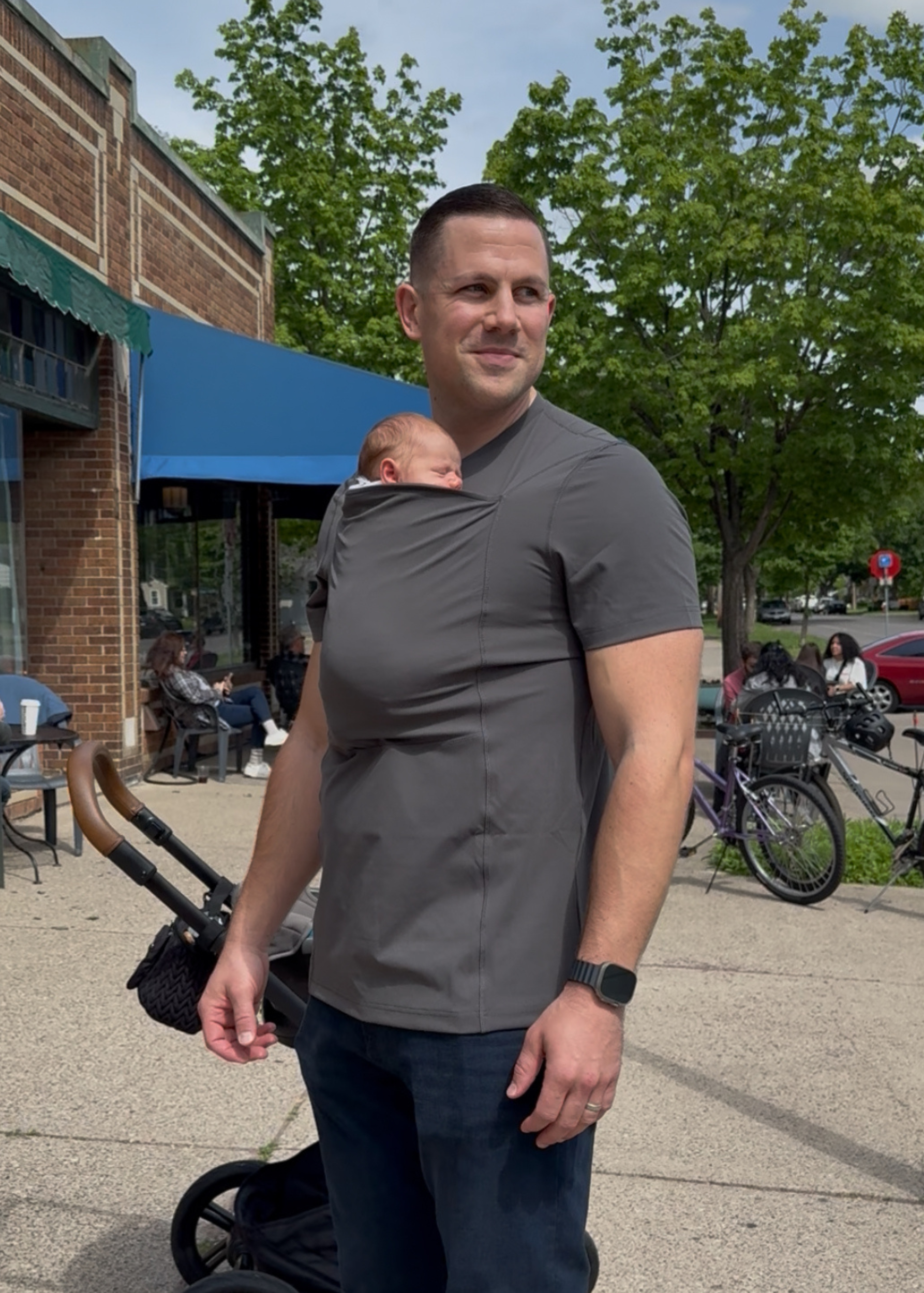 Angled view of a dad wearing his newborn in the pouch of his Gray Dad Shirt.