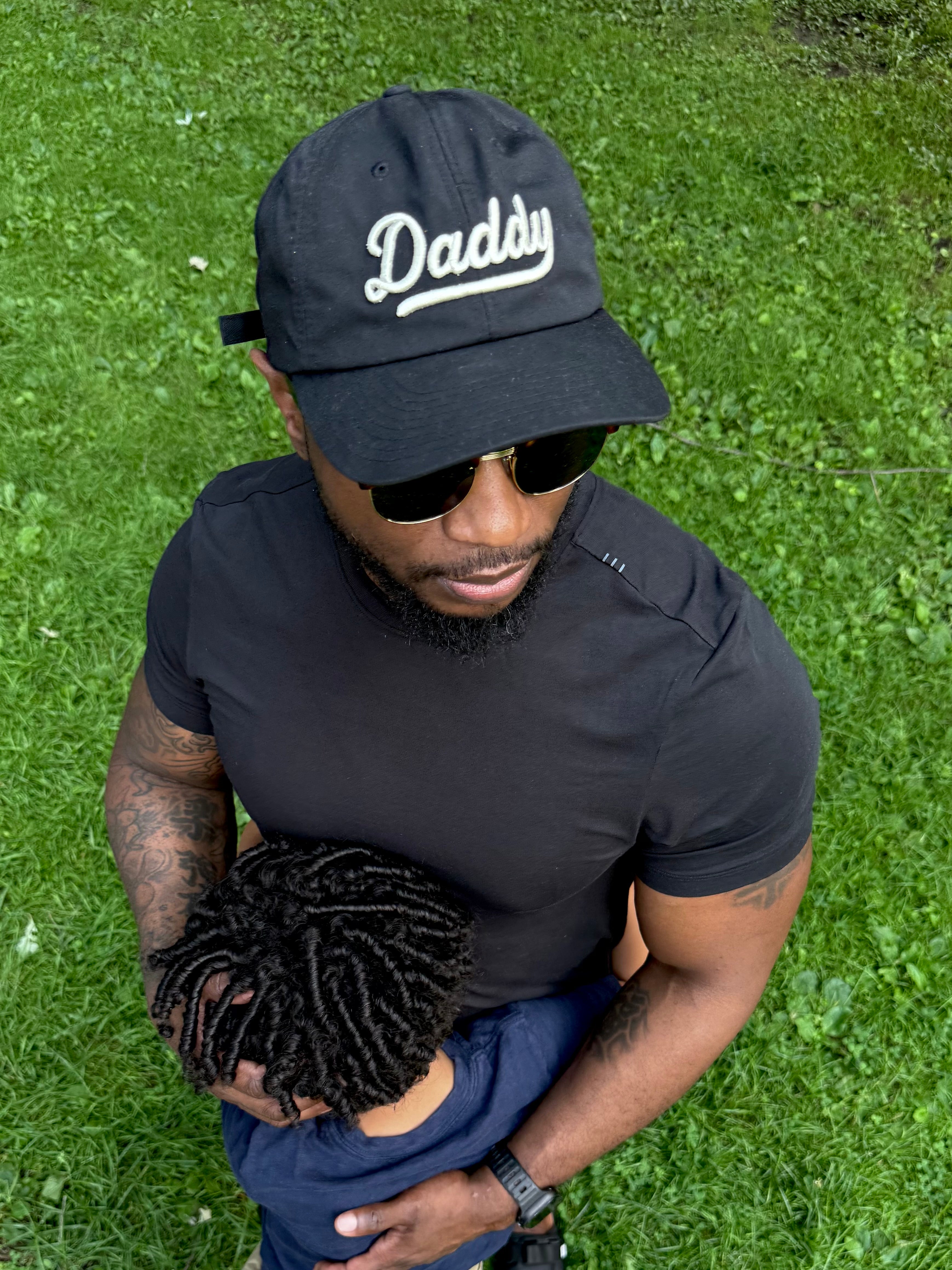 Above view of a dad wearing the "Daddy" hat while hugging his child.