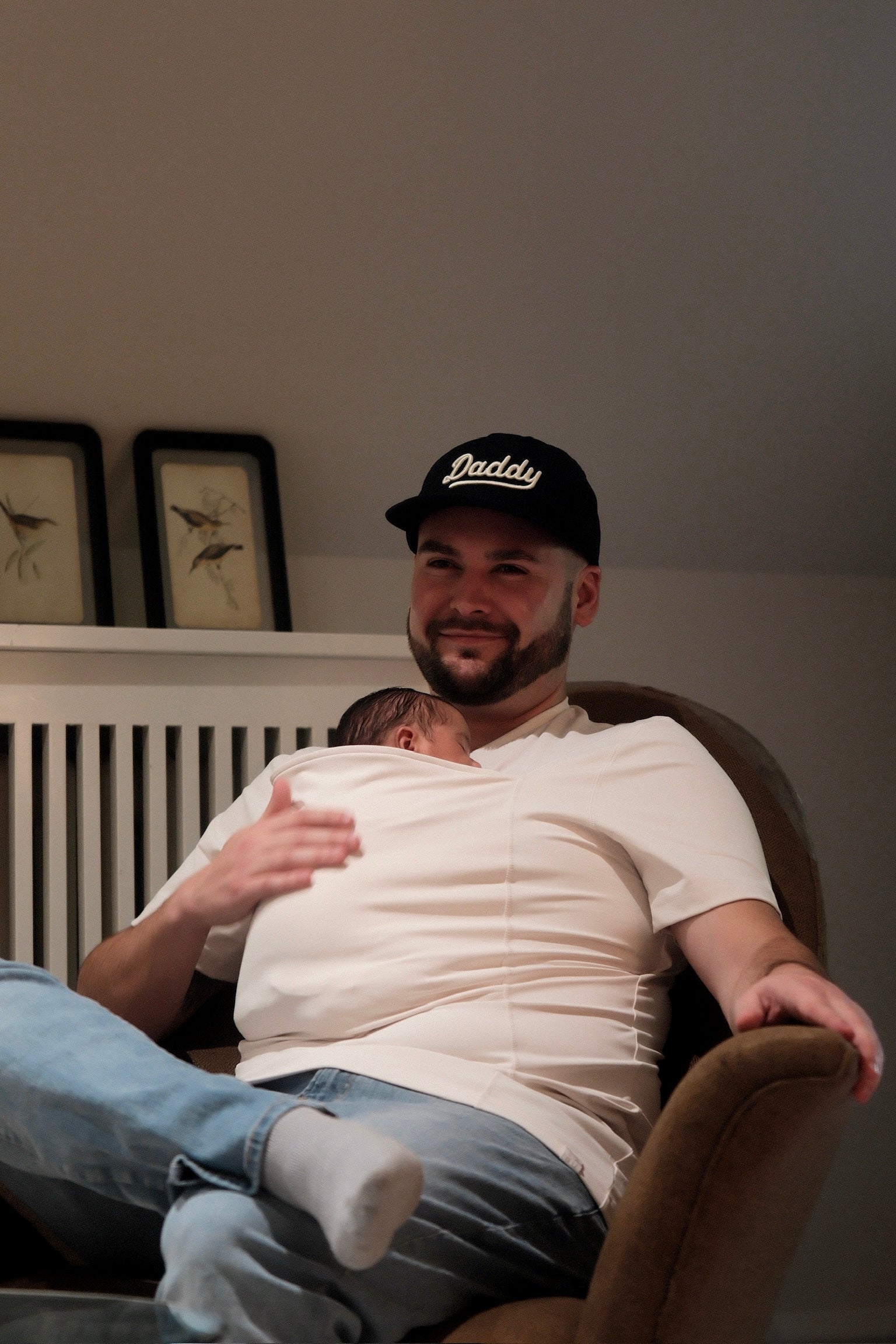 Dad sporting a Daddy Cap and wearing his baby in a Natural Dad Shirt while sitting.