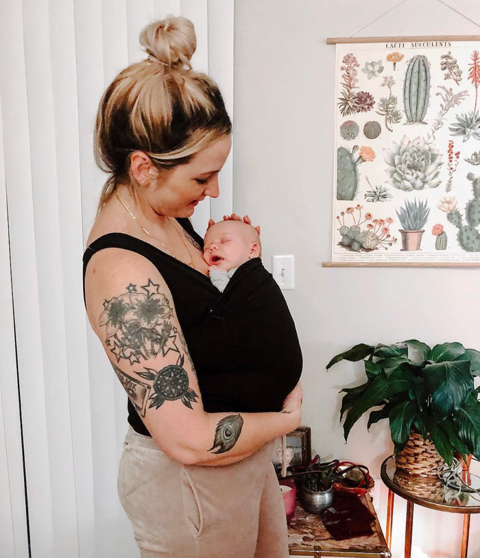 Mom wearing her baby in a Mom Shirt while getting things done