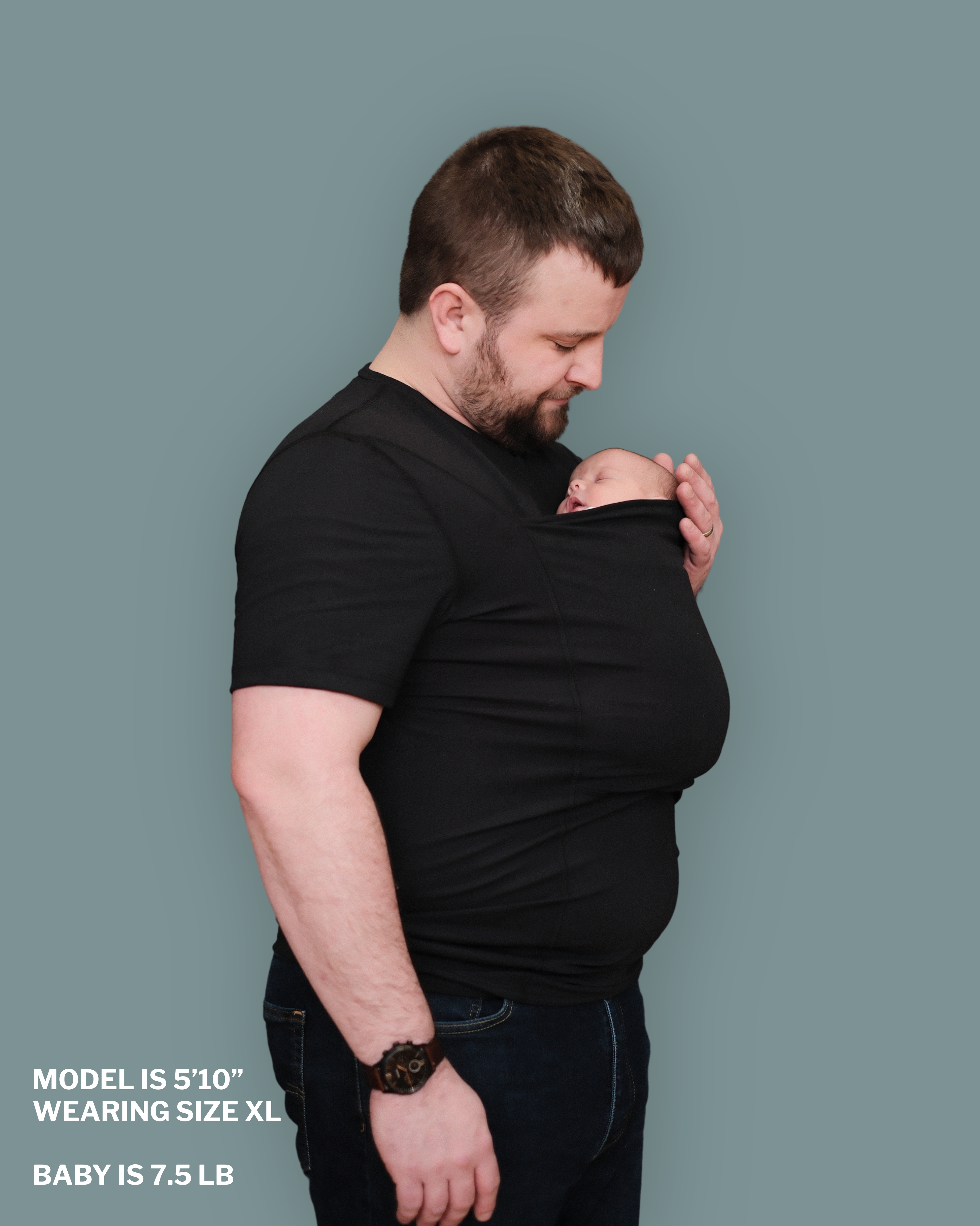 Dad wearing a newborn in a black Dad Shirt. "Model is 5'10", wearing size XL. Baby is 7.5 lbs"
