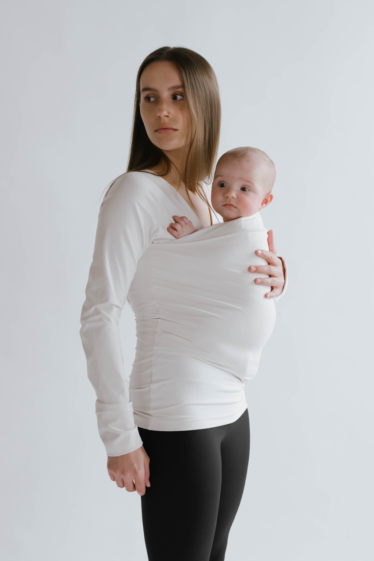 Side view of a female in black high waisted leggings with a newborn in a long sleeve Soothe Shirt.