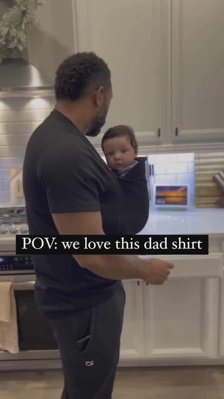 Text: POV: we love this dad shirt. Video shows a dad cooking while wearing newborn in a Dad Shirt.