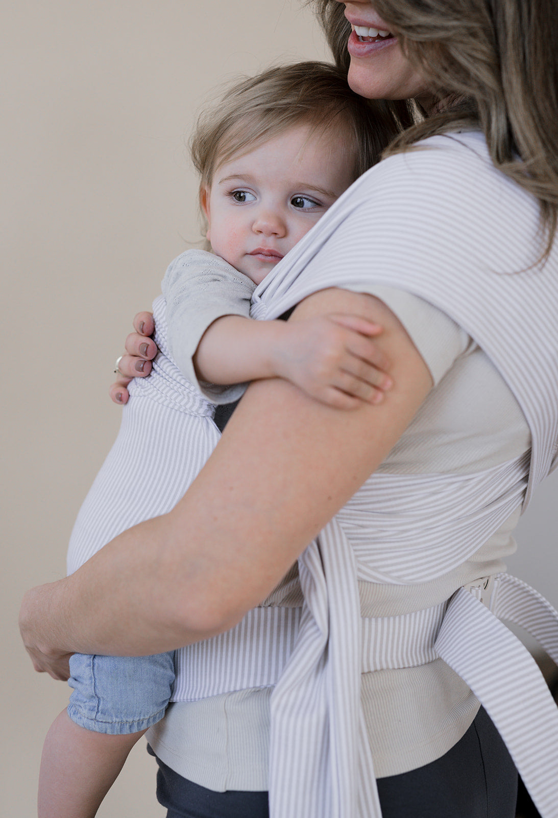 Toddler being front carried in an Oatmeal Stripe Simple Wrap.