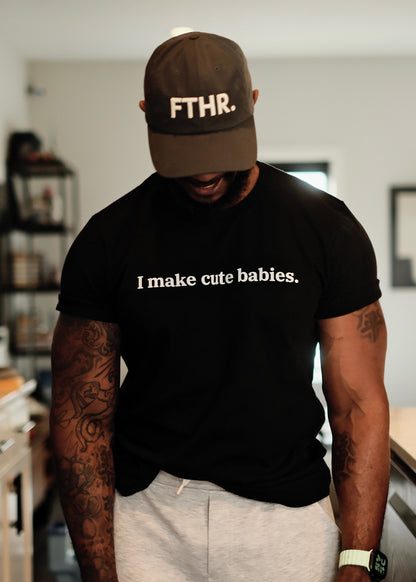 Dad wearing a charcoal cap with 'FTHR.' and a black t-shirt with 'I make cute babies.' text.
