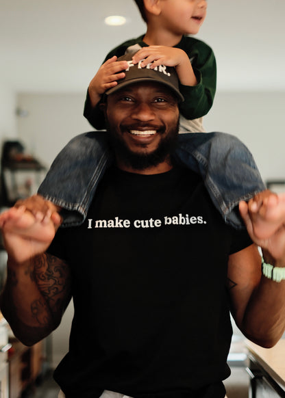 Dad wearing a black t-shirt with 'I make cute babies.' text, holding a child on his shoulders.