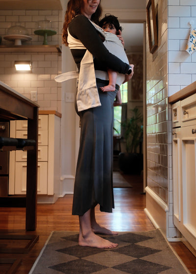 Mom front carrying her baby in a Simple Wrap in the kitchen.