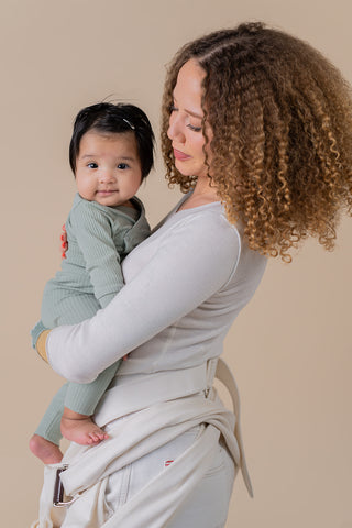 woman dressed in all white holding a baby in her arms.