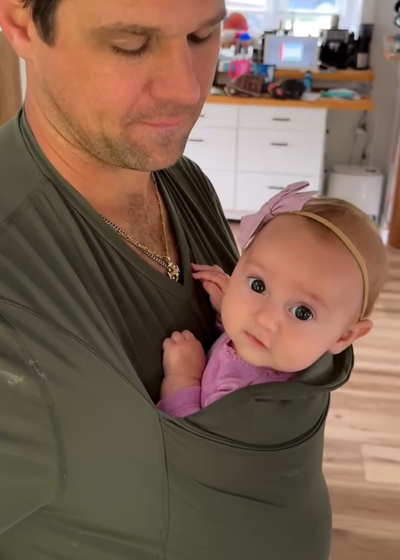 Baby girl stares into the camera from the pouch of Dad's Fern Dad Shirt.