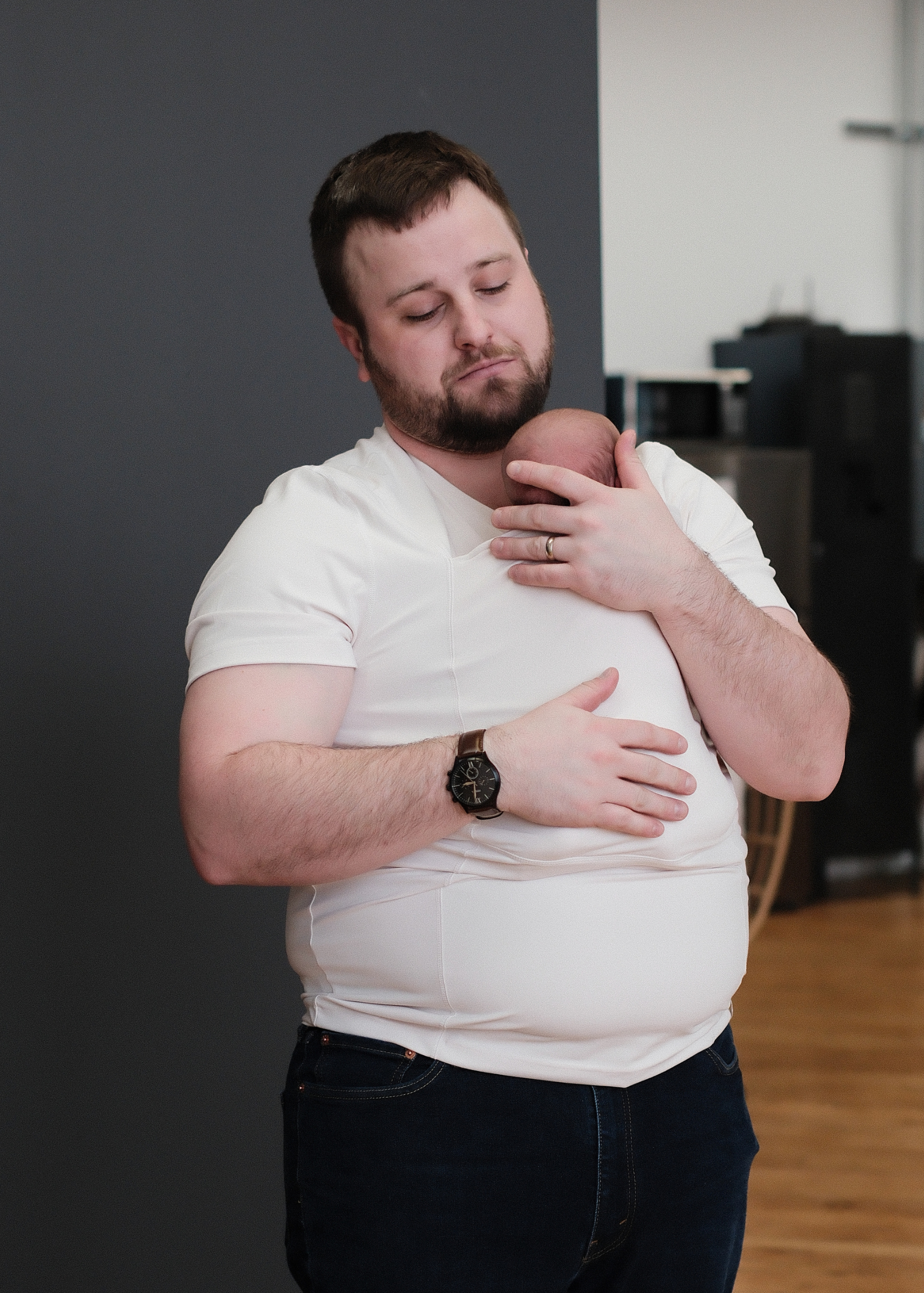 Dad snuggling the baby in the pouch of his Natural Dad Shirt.
