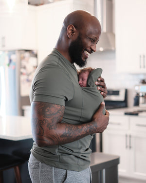 Dad wearing newborn in Dad Shirt in a kitchen.