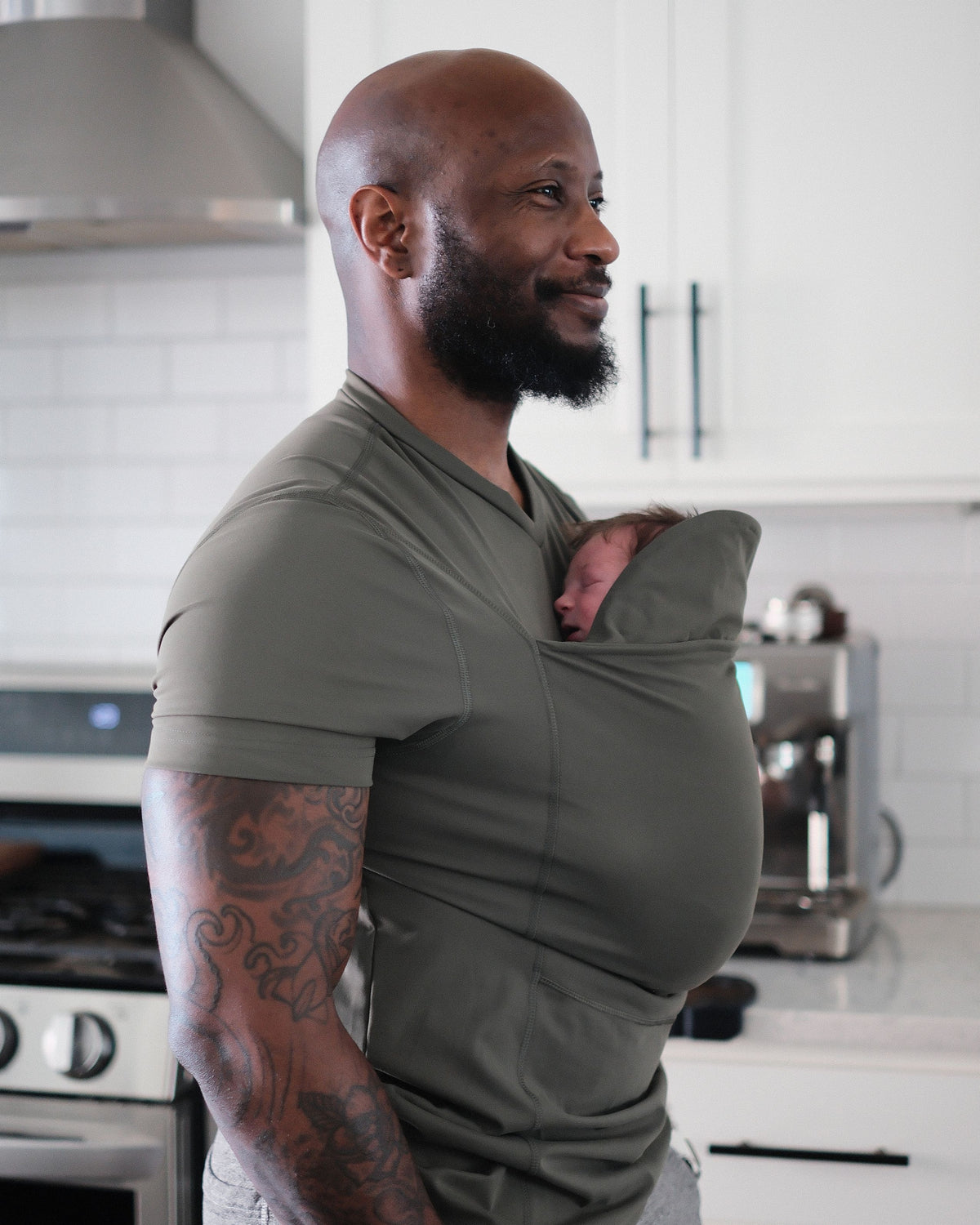 Dad wearing newborn in Dad shirt in a kitchen.