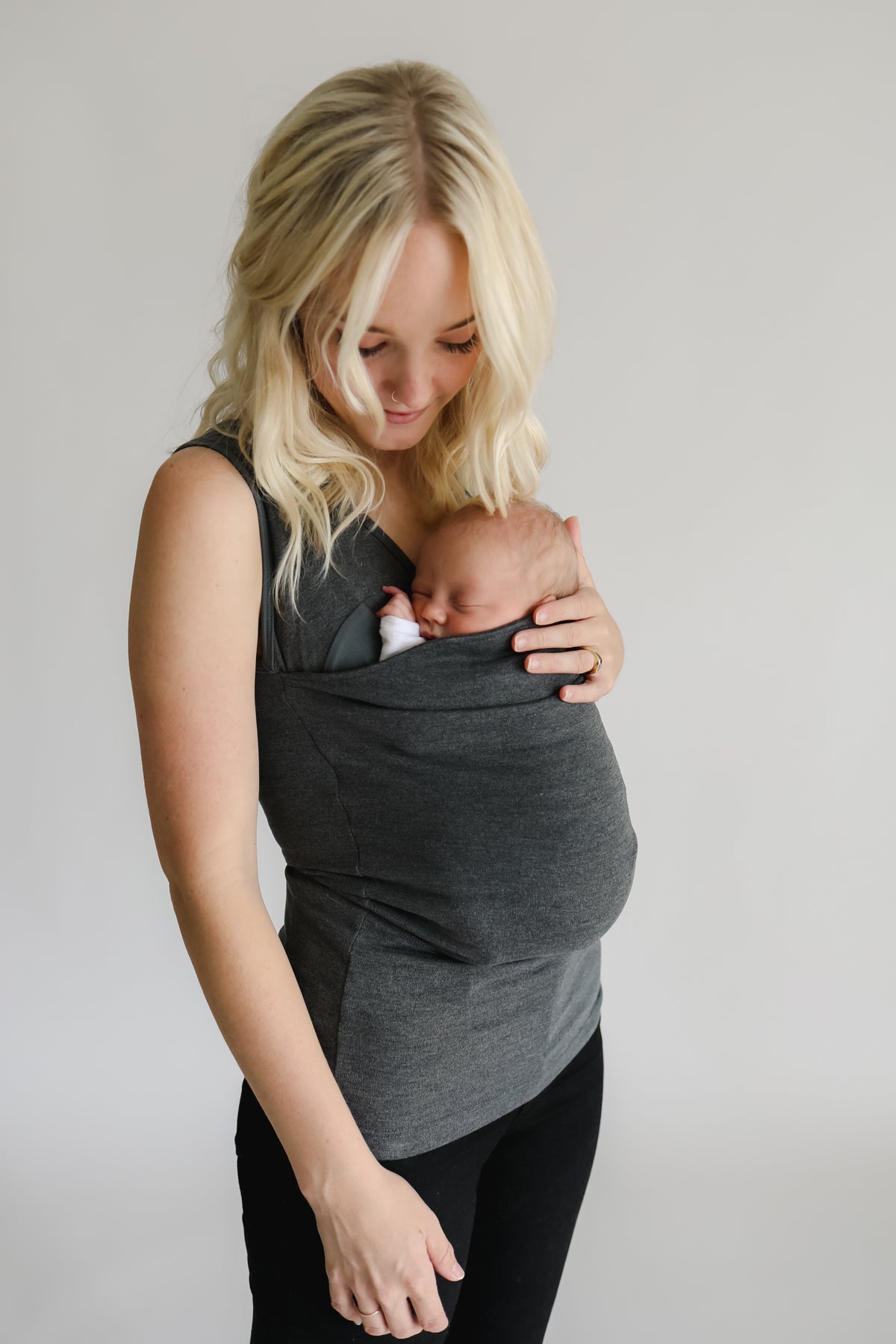 Mom wearing a newborn in a gray soothe shirt.