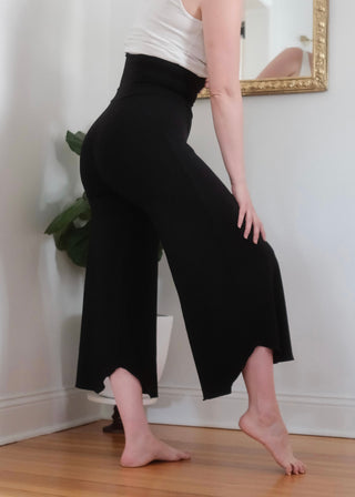 Female modeling the black flow pants which hit mid calf with a high waist.