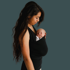 Side profile of a mom wearing a newborn in a black Soothe Shirt.