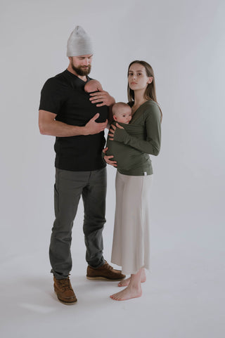 Dad with his baby in a Dad Shirt next to Mama in Natural Flow Pants with her baby in a Soothe Shirt.