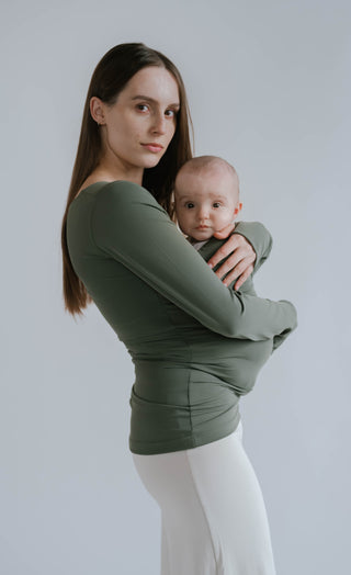 Side view of a female wearing a newborn in a Fern long sleeve Soothe Shirt.