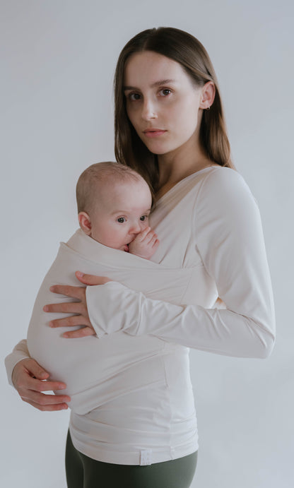 Side view of a female wearing a newborn in a Natural long sleeve Soothe Shirt.