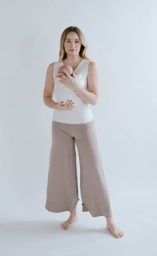 Full body view of a female wearing a newborn in a Natural Soothe Shirt.