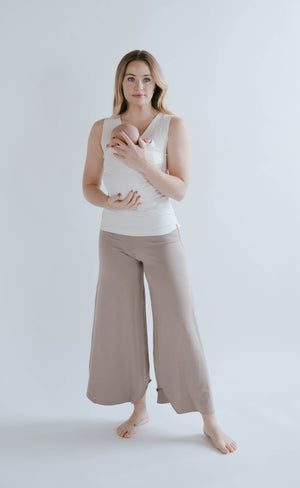 Female in Flax Flow Pants wearing her newborn in a Natural Soothe Shirt.