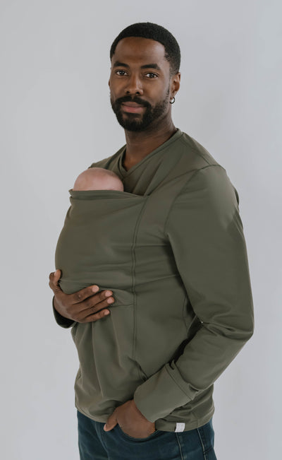 Dad looking at the camera, wearing his newborn in the pouch of a long sleeved Fern Dad Shirt.