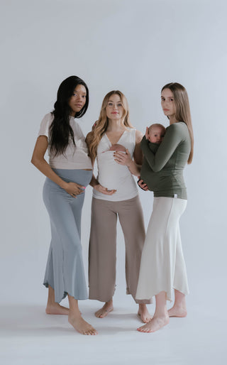 Full body view of 3 females, one is pregnant, 2 are wearing newborns in Soothe Shirts.