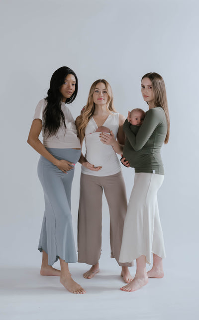 Full body view of 3 females, one is pregnant, 2 are wearing newborns in Soothe Shirts.