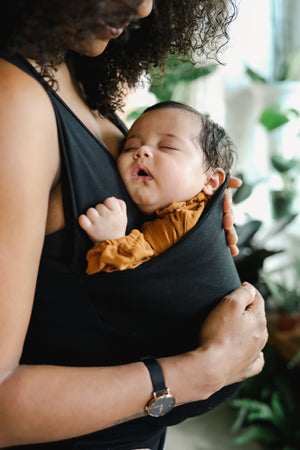 Close up of a newborn worn in a Black Soothe Shirt.