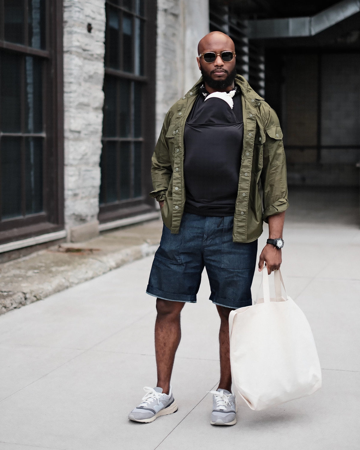 Dad wearing a newborn in a black Dad shirt, in front of a building.