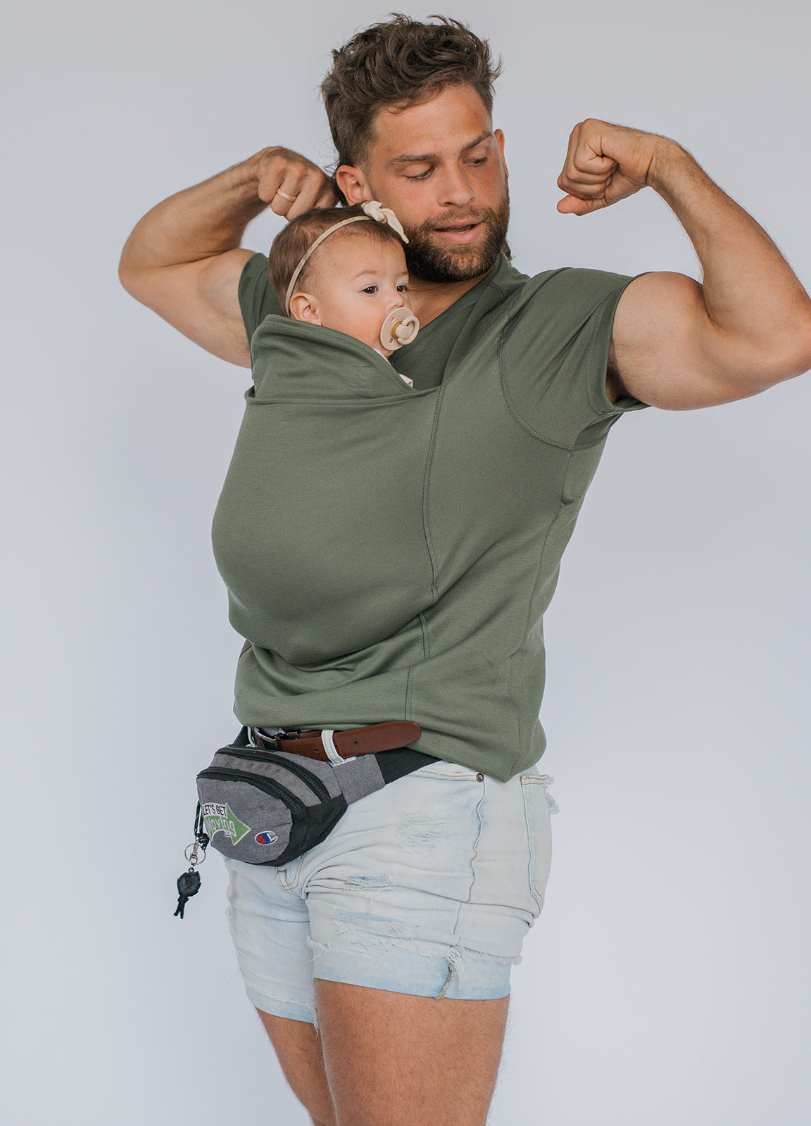 Dad flexing while wearing newborn in a Dad Shirt.