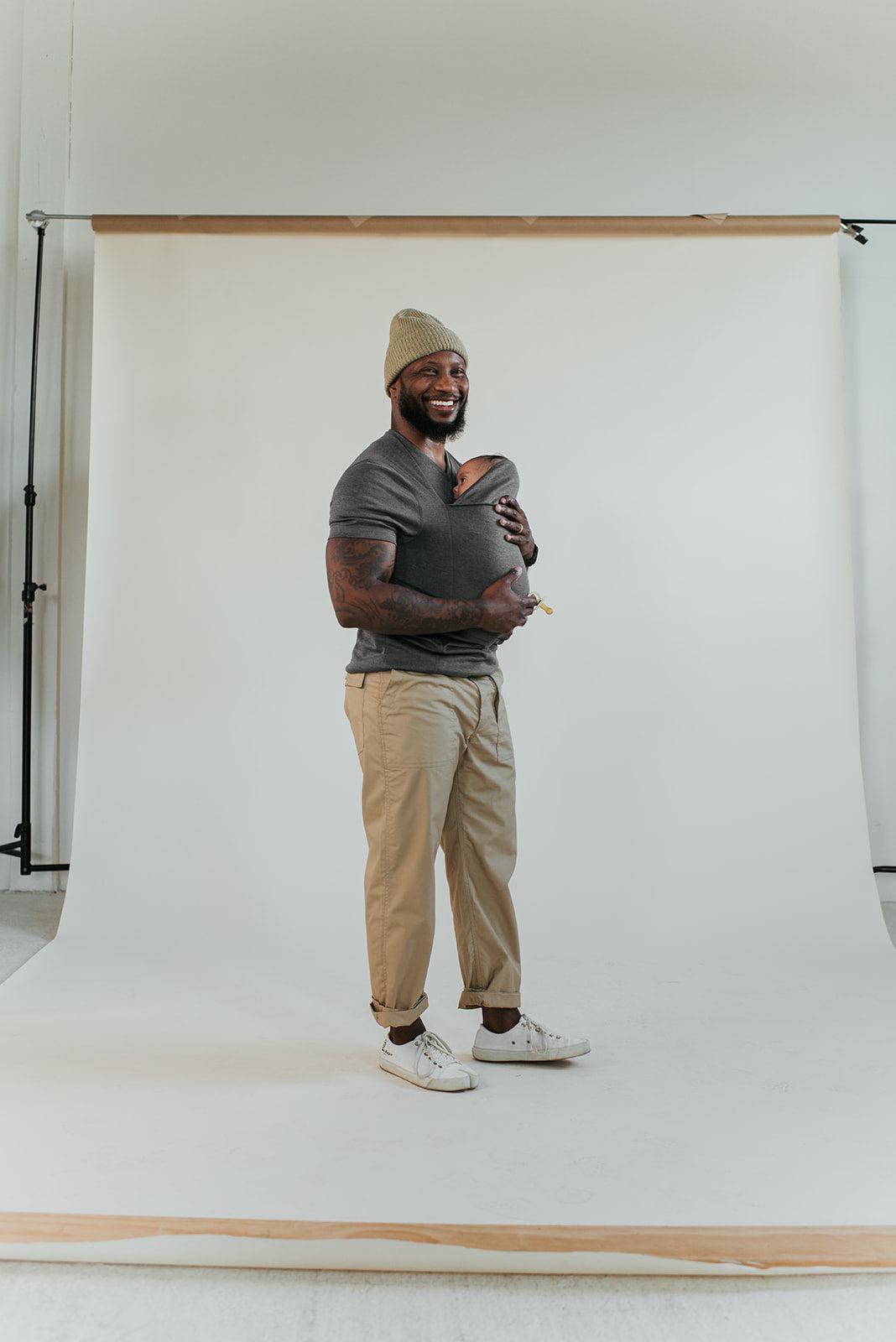 Full body view of a dad wearing his newborn in a Dad Shirt.