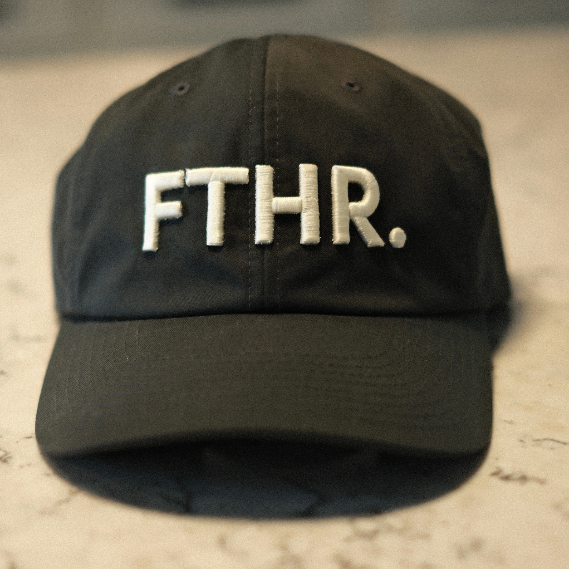 Charcoal gray ball cap with off white 3d embroidery of "FTHR."