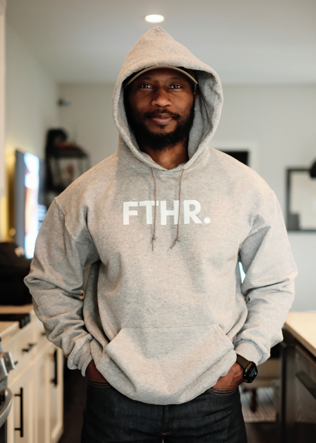 Man wearing a gray hoodie with 'FTHR.' text in a casual indoor setting