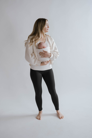 Female wearing black high waisted leggings and a newborn in a Soothe Shirt.