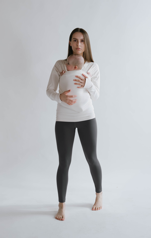 Front view of a female in gray high waisted leggings with a newborn in a long sleeve Soothe Shirt.