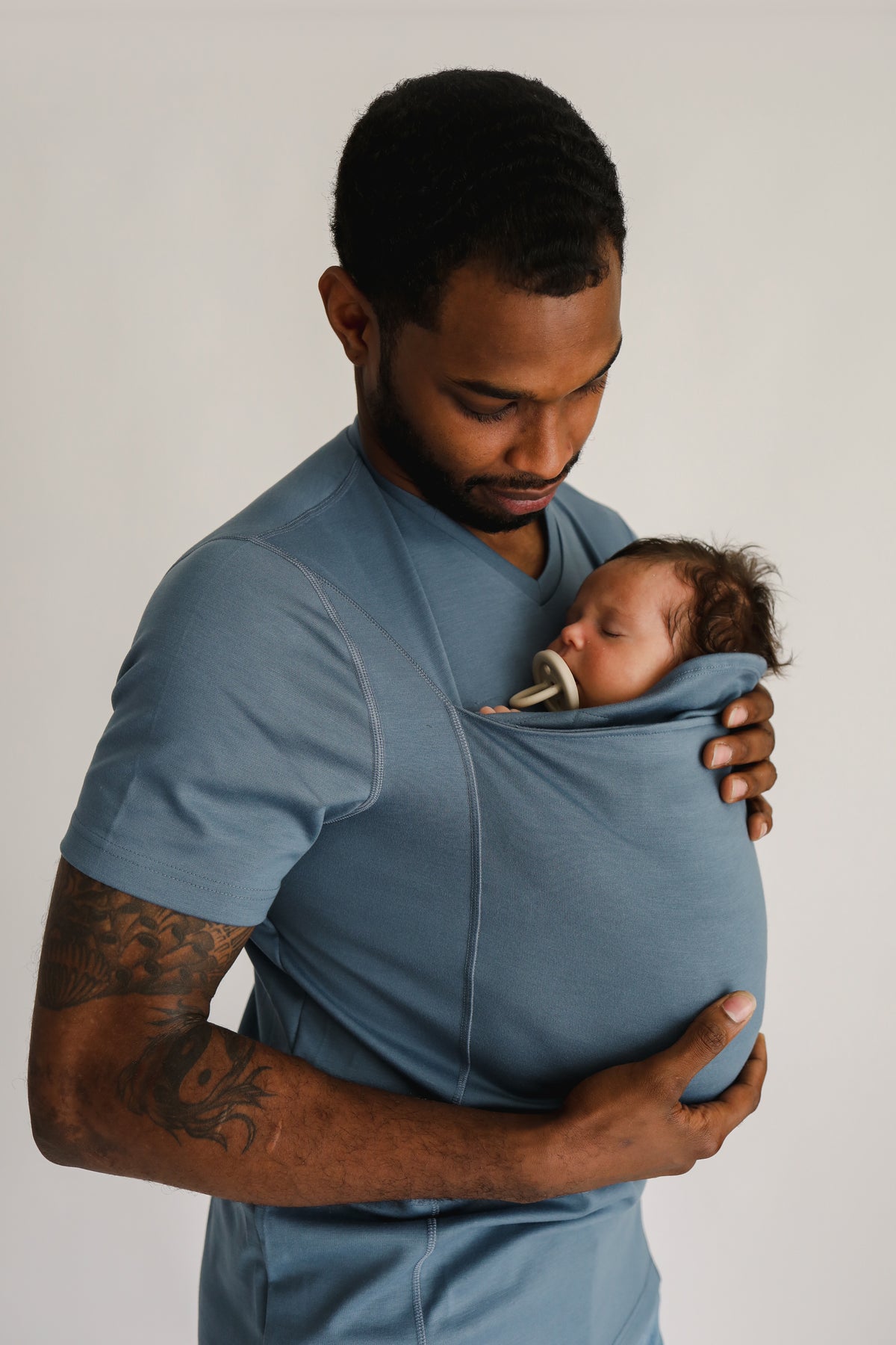 Angled view of a dad wearing a newborn in a Brook Dad Shirt.