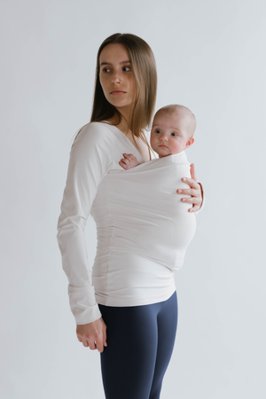 Side view of a female in navy high waisted leggings with a newborn in a long sleeve Soothe Shirt.
