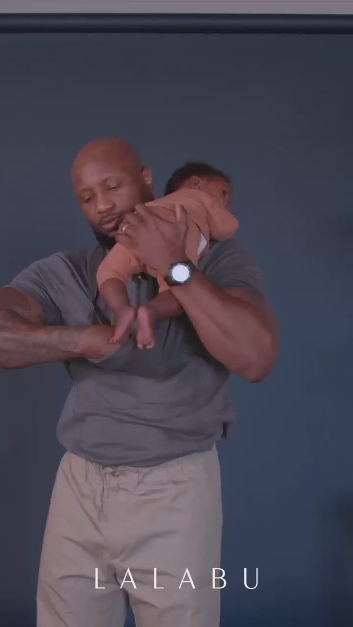 With baby on Dad's shoulder, he pulls the Dad Shirt pouch open and slides baby in, while pulling the pouch up.