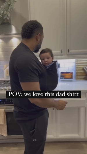 Text: POV: we love this dad shirt.  Video shows a dad cooking while wearing newborn in a Dad Shirt.