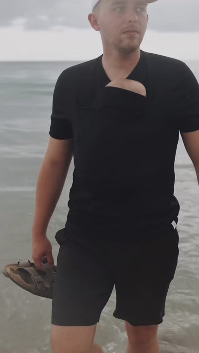 Dad enjoying some time at the beach with his newborn in the pouch of his Black Dad Shirt.