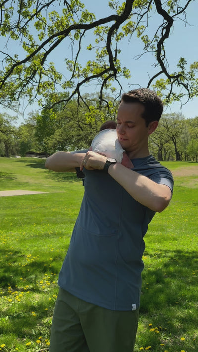 Dad opens the pouch of his Brook Dad Shirt and slides baby into it from his shoulder.