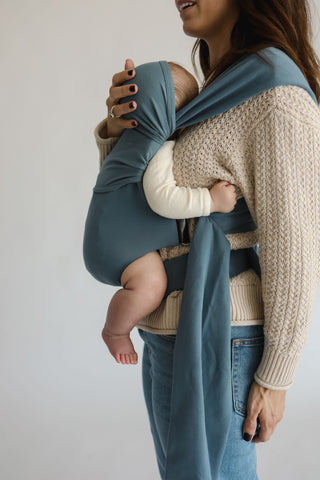 Side view of a female front carrying a baby in a Brook Simple Wrap.
