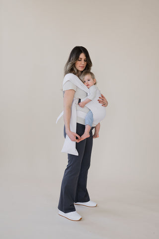 Full body view of a pregnant female front carrying a baby in an Oatmeal Stripe Simple Wrap.