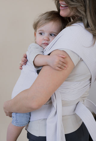 Side view of a pregnant female front carrying a baby in an Oatmeal Stripe Simple Wrap.